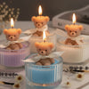 A collection of soy wax teddy bear candles in glass jars with ribbons, featuring orange and light brown bears.