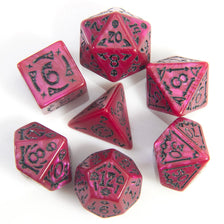 Un jeu de sept dés polyédriques roses et violets posés sur une surface blanche.