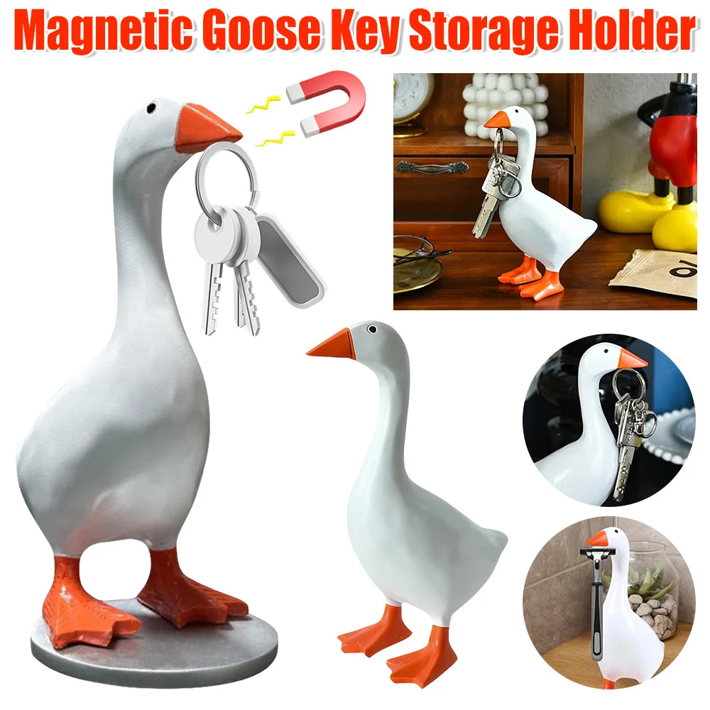A white resin goose figurine with an orange beak and legs, shown alongside magnetic key holders.