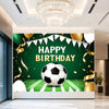 A green backdrop for a birthday celebration featuring a soccer ball, gold balloons, and confetti.
