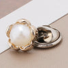A close-up of a gold-toned pearl and rhinestone no-sew brooch button with a floral design.