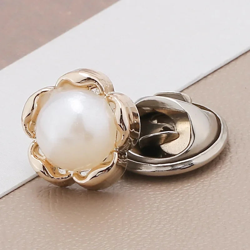A close-up of a gold-toned pearl and rhinestone no-sew brooch button with a floral design.