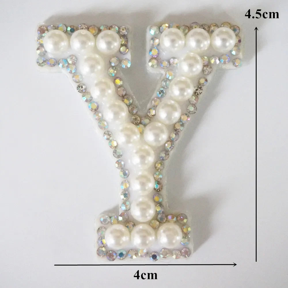 A white pearl and rhinestone alphabet letter V patch with dimensions 4.5cm high and 4cm wide.