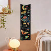 A vertical tapestry featuring celestial elements like the sun, moon, and various mushrooms and flowers on a black background.