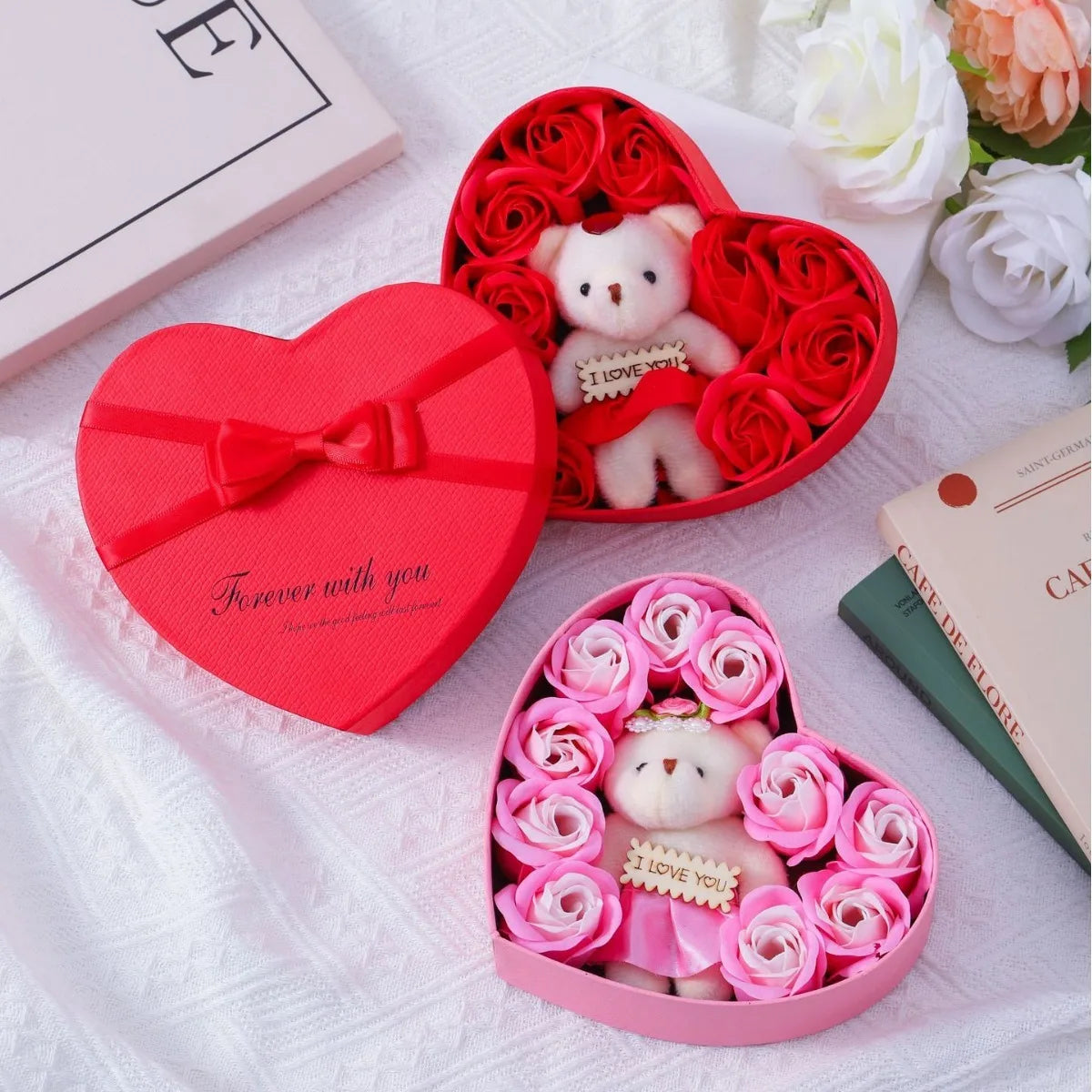 A pink heart-shaped gift box filled with red roses and a small white teddy bear.