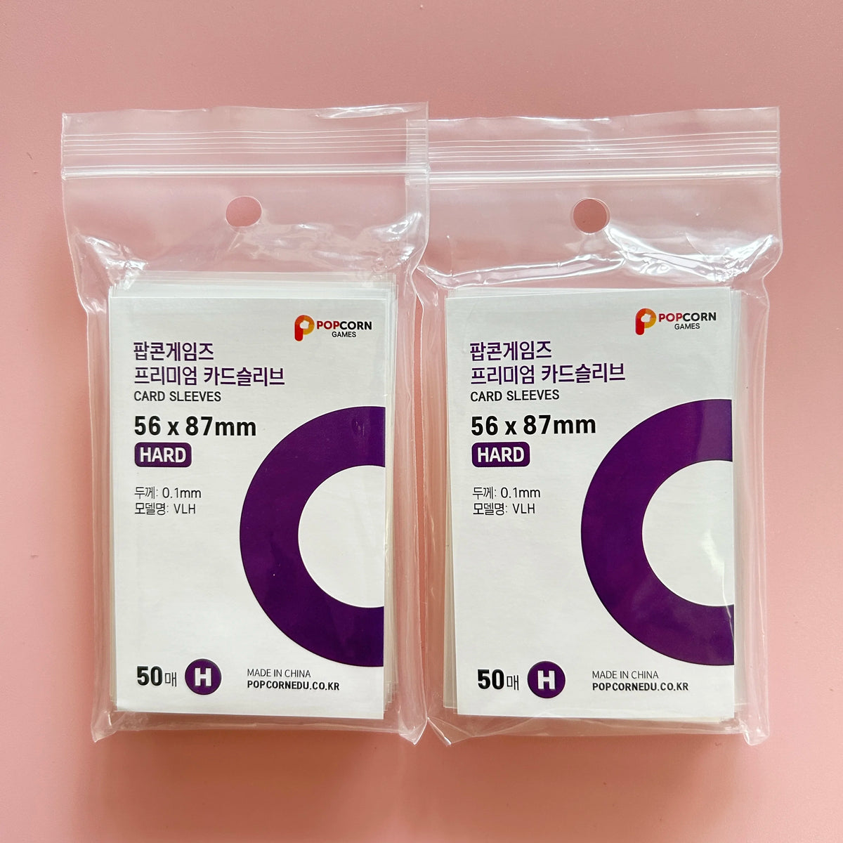 Two clear plastic bags containing 50 packs each of purple card sleeves labeled as premium card sleeves