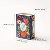 A ceramic book-shaped vase with a vintage finish featuring floral patterns and text on the side.