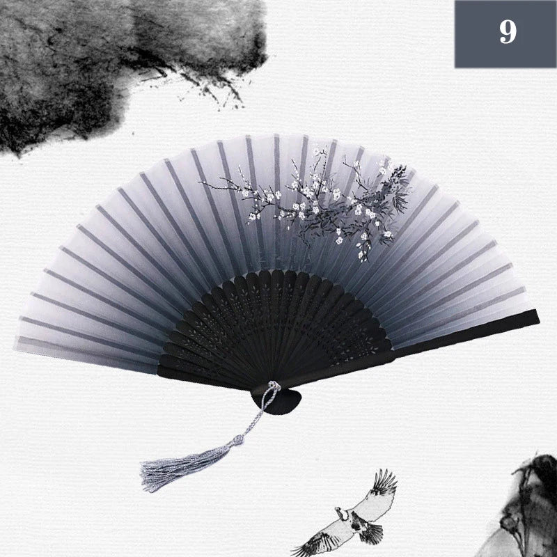 A black and white image of a vintage silk bamboo folding hand fan with delicate floral accents.