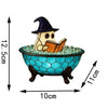 A cute ghost figurine wearing a witch hat is sitting in a blue bowl filled with clear gems, reading an open book.