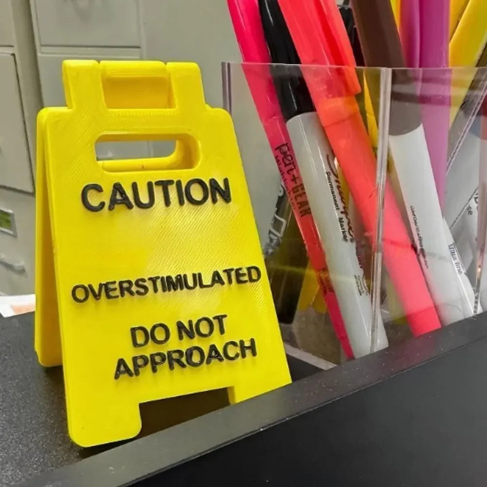A yellow plastic desk sign with black text warning caution and do not approach.