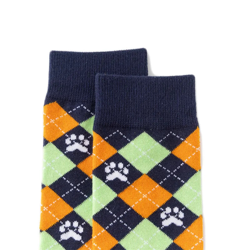 A pair of navy blue crew socks featuring a diamond pattern with orange and lime green accents and white paw prints.