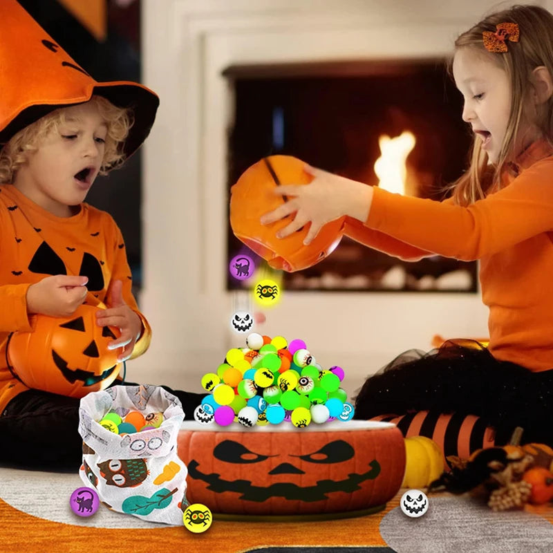 Two children play with a set of glow-in-the-dark Halloween bouncing balls and a carved pumpkin.