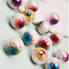 Un ensemble de dix perles de séparation pour yeux en acrylique irisées avec des designs colorés et détaillés, éparpillées sur