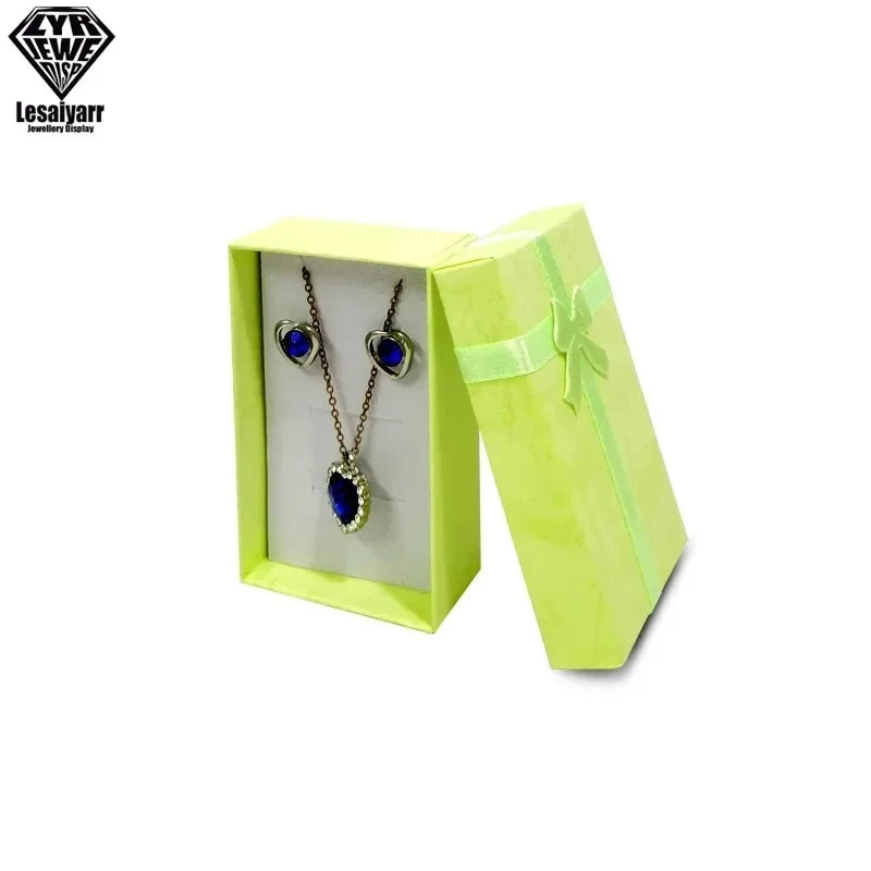 Un par de pendientes de gema azules mostrados dentro de una caja de regalo de joyería verde claro.