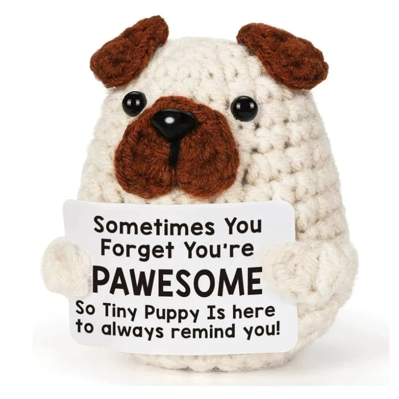 A handmade crochet potato doll with brown ears and a white body holding an inspirational card.