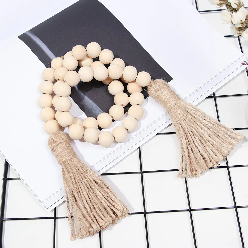 Boho farmhouse tassel bead wall hanging featuring a wreath of light beige wooden beads on a white background.