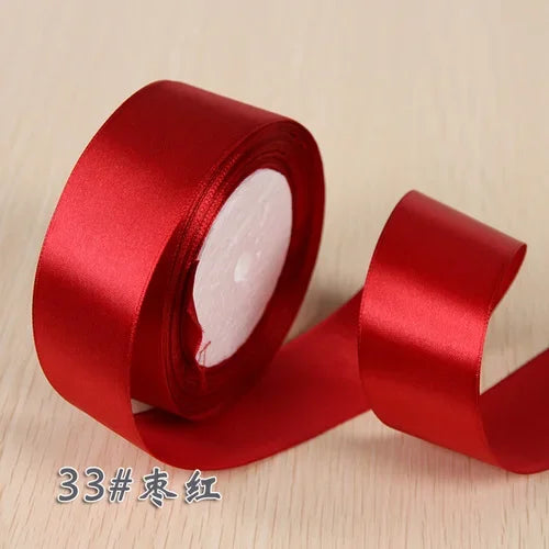 A roll of red silk satin ribbon used for gift wrapping and craft projects.