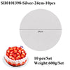 A round white cake board with a silver coating is shown next to a strawberry cake.