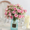 A bouquet of pink and blush roses in a glass vase with greenery for home or event decor.