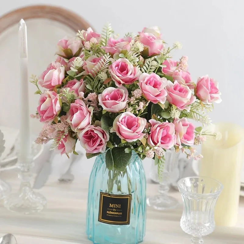 A bouquet of pink and blush roses in a glass vase with greenery for home or event decor.