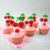 A collection of pink frosted cupcakes decorated with red cherries and green leaves.