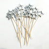 A cluster of silver star-shaped cocktail picks with pearl tips on bamboo sticks.
