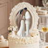 Elegant wedding cake topper featuring a bride and groom in white attire surrounded by floral accents.