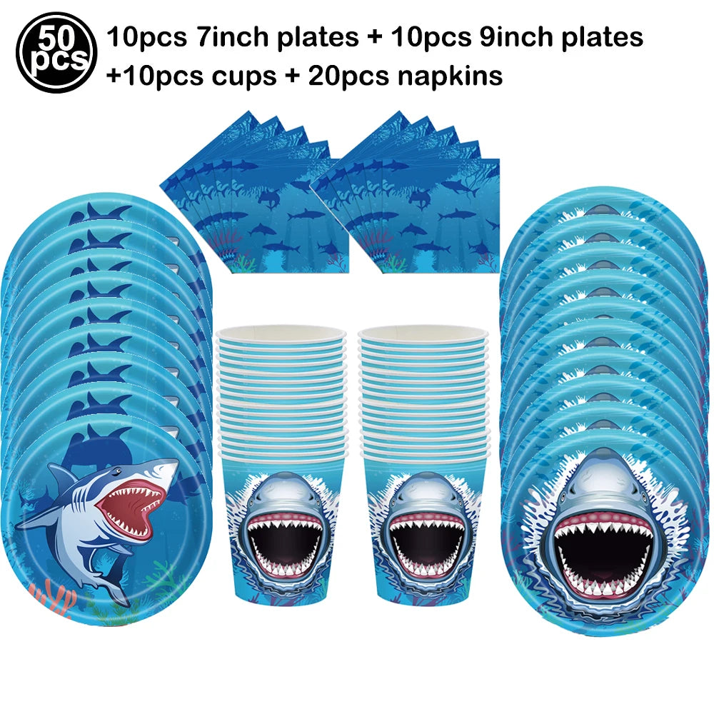 A set of blue shark themed plates, cups, and napkins for a party decoration.