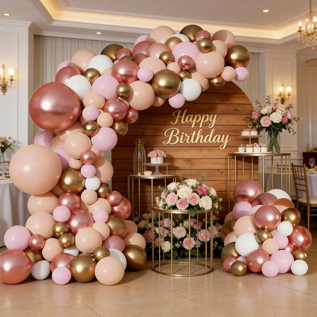 A large balloon garland featuring rose gold and pink balloons arranged in an archway against a wooden backdrop.