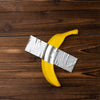 A yellow banana sculpture wrapped in silver fabric resting on a dark wooden surface.