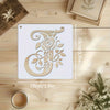 A white reusable floral alphabet stencil shaped like the letter O is displayed on a wooden surface.
