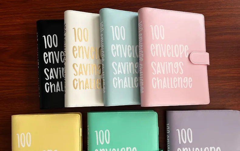 A collection of pink, mint green, beige, and black 100 envelope challenge binders for cash savings organization.