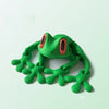 A bright green, movable 3D printed tree frog ornament with orange eyes.