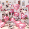 A collection of pink and silver heart foil balloons displayed against a white wall.