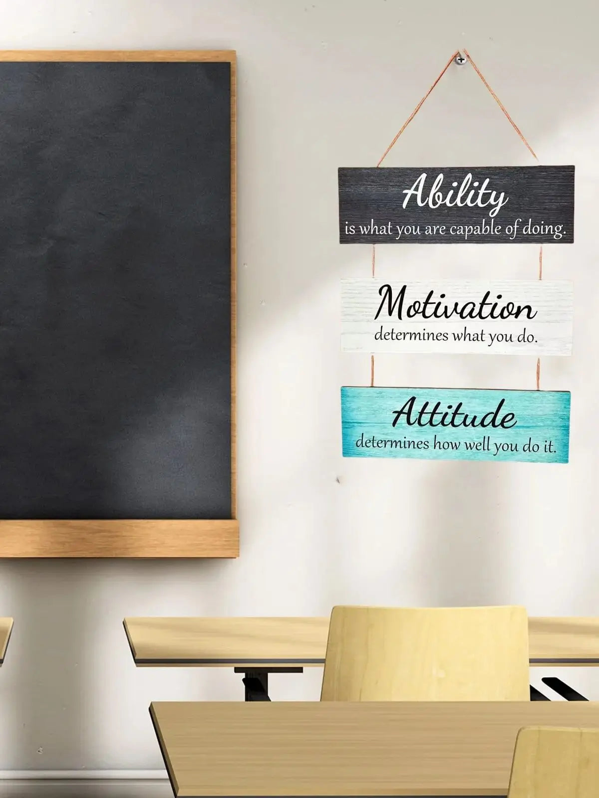 A rustic wooden inspirational hanging sign featuring text about ability, motivation, and attitude on a white wall.