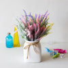 A bouquet of romantic lavender artificial flowers in various shades of purple, pink, and yellow displayed in a white vase.