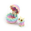 A 3D printed dragon egg is cracked open, revealing a small, light purple and pink dragon toy inside.