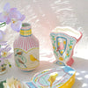 A yellow ceramic bird floral vase and matching decor items displayed on a white surface.