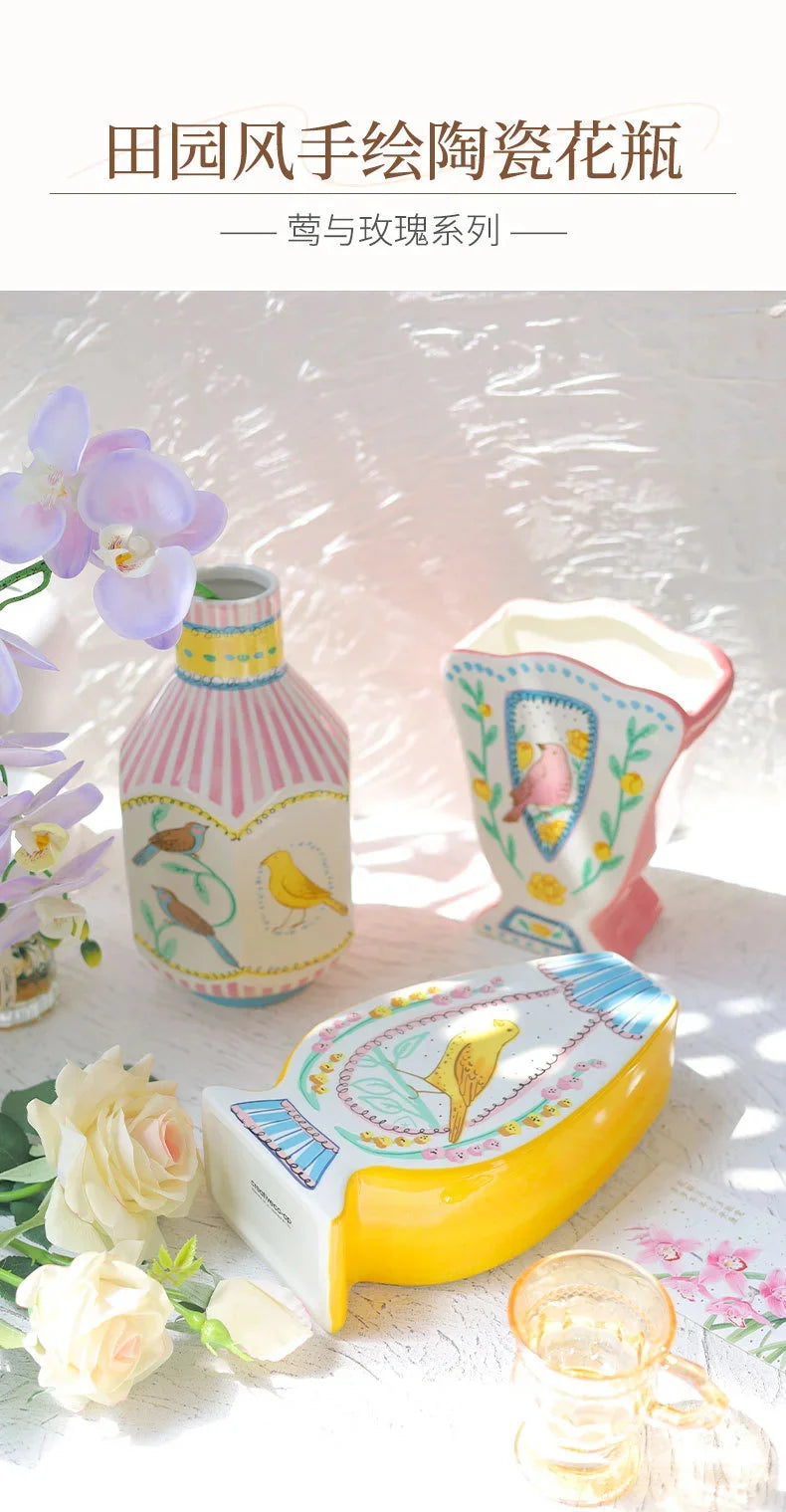 A yellow ceramic bird floral vase and matching decor items displayed on a white surface.