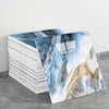 Stack of faux marble 3D self-adhesive wall tiles featuring blue and gold veining on a gray background
