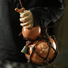 A hand holds a traditional ceramic wine gourd used for hot water and beverages.