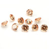 A collection of loose, round cut cubic zirconia stones in various sizes and shades of warm gold and amber.