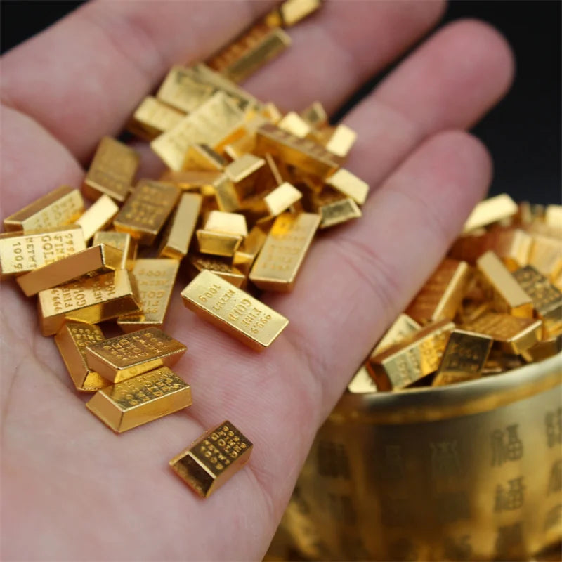 A hand holds a pile of small, rectangular gold bars used as decor.