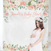A pregnant woman in a pink dress stands in front of a floral tapestry announcing Jennifer's baby shower.
