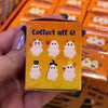 A hand holds a cardboard box of six peel-and-stick ghost phone decoration charms.