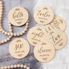 A collection of natural wood signs with numbers and months, including hello world, twelve months, three months, eight months,