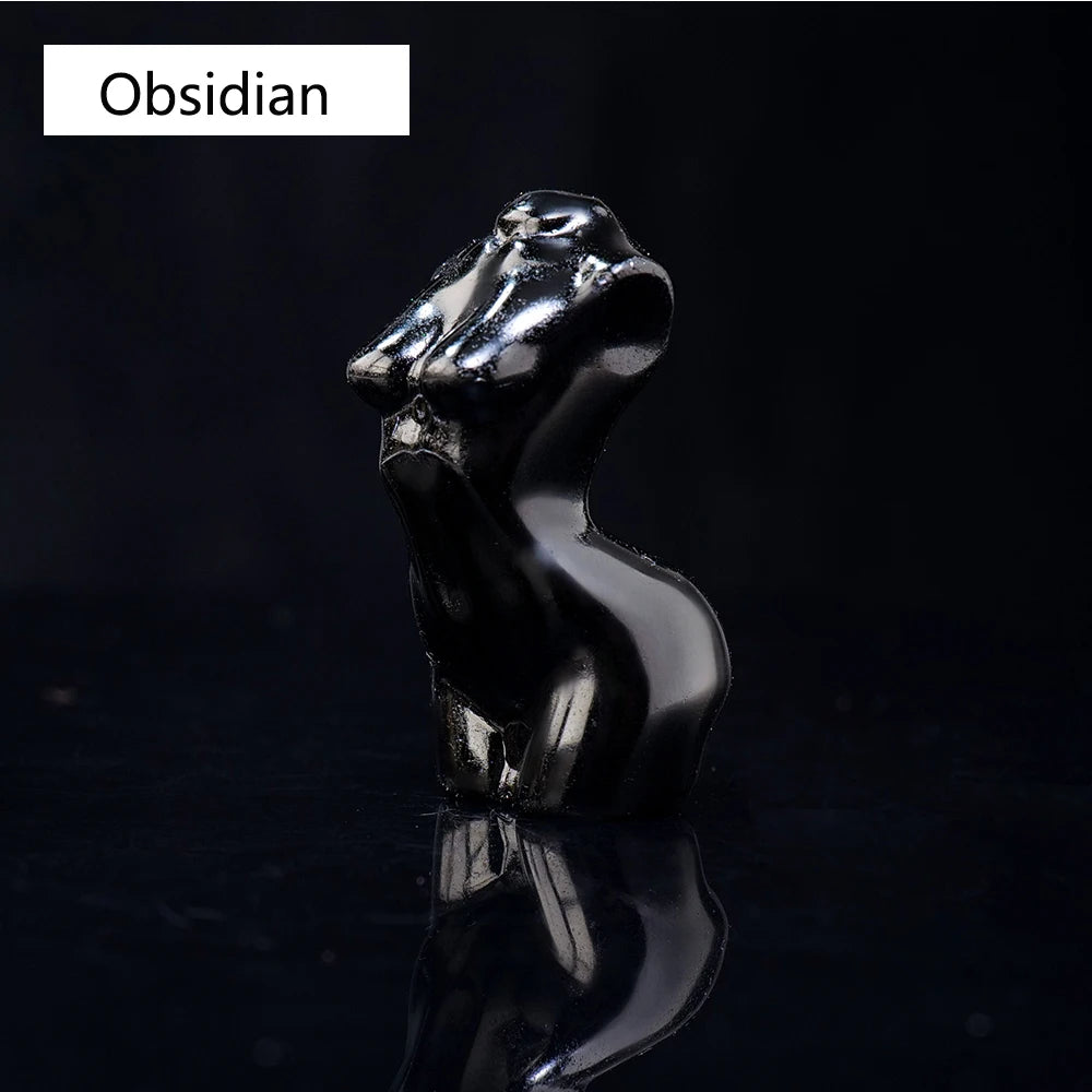 Figura de obsidiana negra y brillante con cabeza de animal estilizada, reflejando en una superficie oscura.