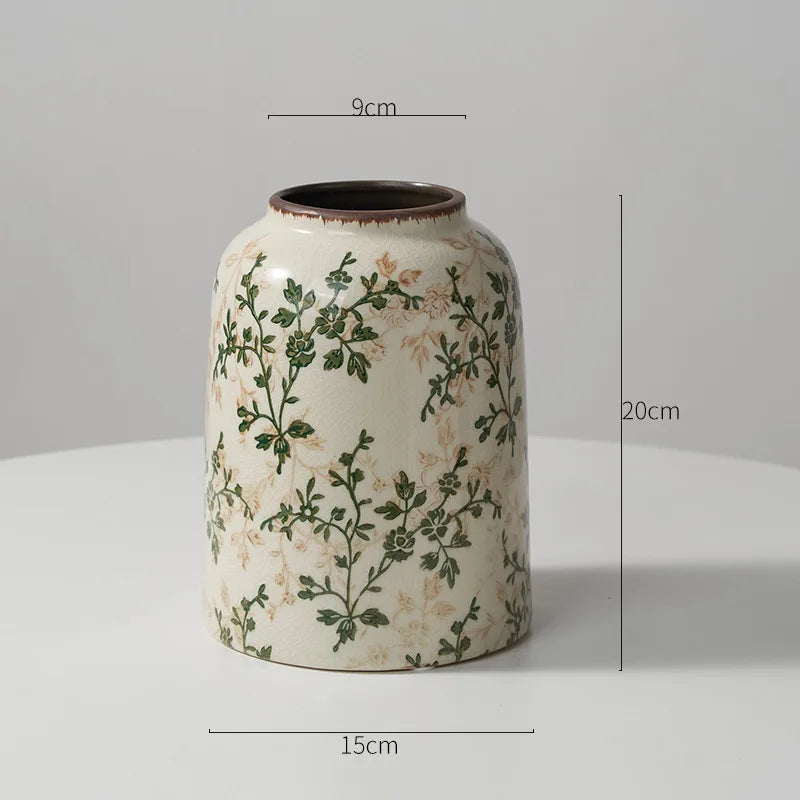 A rustic ceramic milk pitcher with a pale cream glaze and pastoral green floral design.