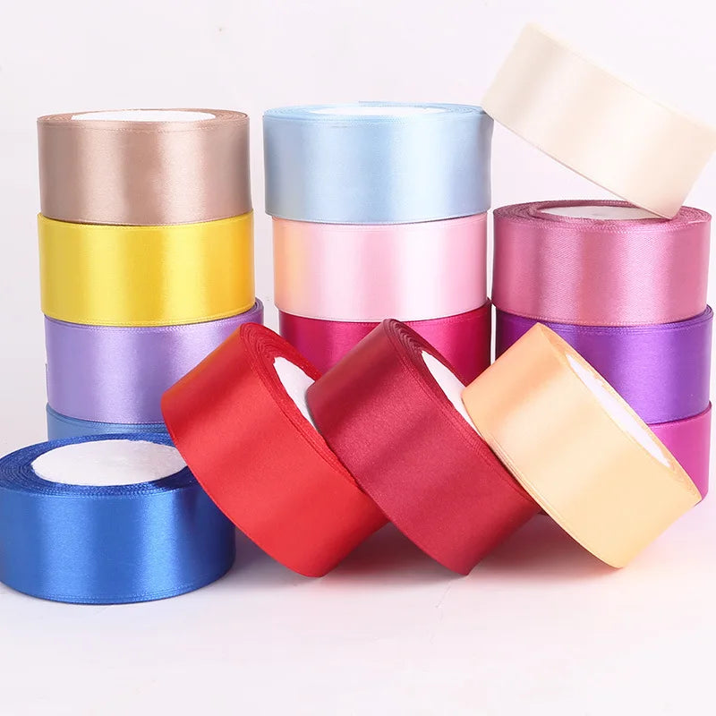 A collection of rolled satin ribbon in various shades including pink, purple, yellow, and red.