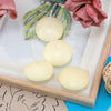 A collection of creamy yellow floating candles displayed in a wooden frame with pink and green floral accents.